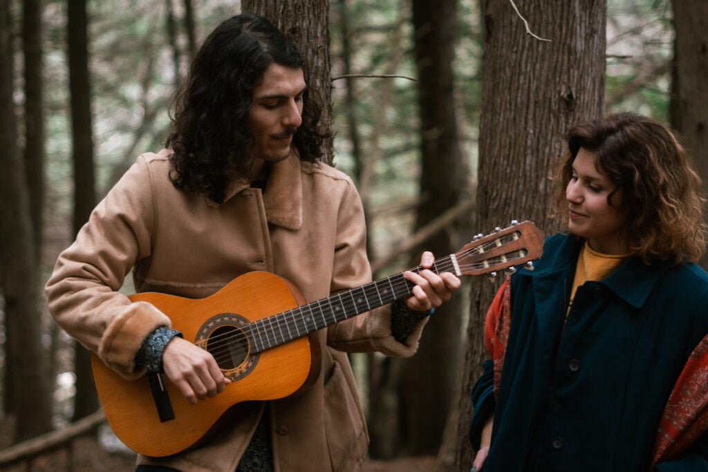 Le duo Noem poem avec Xavier Harel à la guitare et Noem qui sourit, dans la forêt.
